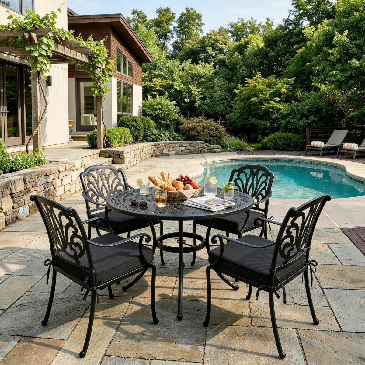 Black outdoor seat cushions on patio chairs with a round outdoor dining table in a backyard setting.