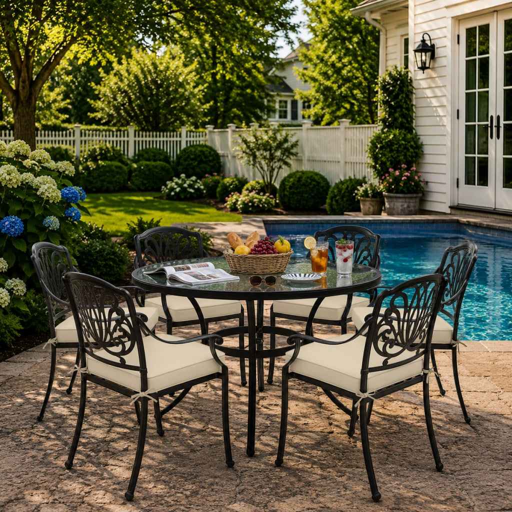 outdoor seat cushions in beige on black metal patio chairs, styled in a sunny backyard garden with a small round outdoor table