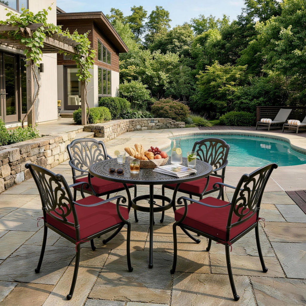 outdoor seat cushions in burgundy on black metal patio chairs, styled around a round dining table in a backyard pool area