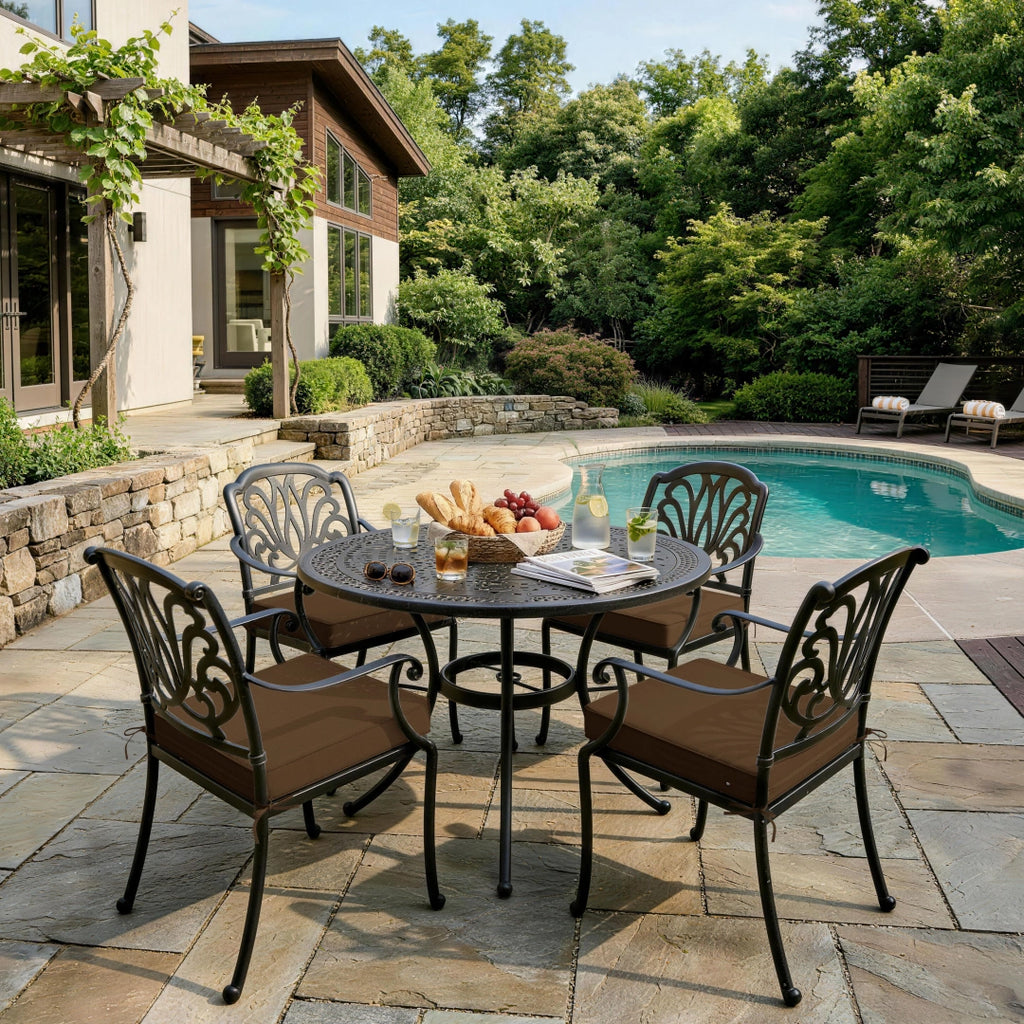 outdoor seat cushions in chocolate brown on black metal patio dining chairs, styled around a round outdoor table beside a backyard pool