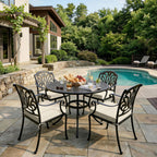 outdoor seat cushions in cream on black metal patio dining chairs, shown around a round table beside a sunny backyard pool