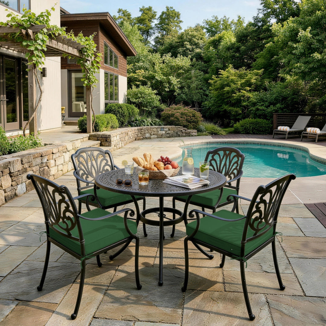 outdoor seat cushions in dark green on black metal patio dining chairs, styled in a sunny backyard poolside dining space