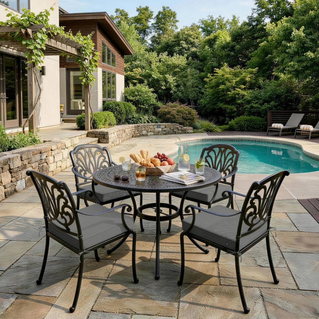 outdoor seat cushions in gray on black metal patio dining chairs, styled around a round outdoor table near a pool