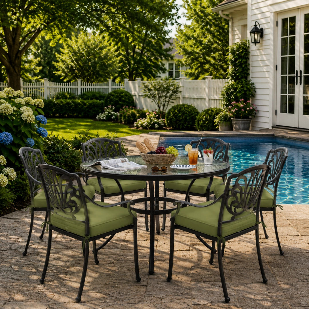 outdoor seat cushions in dark green on black metal patio chairs, styled in a sunny backyard garden with a small round outdoor table