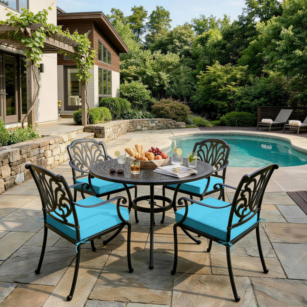 outdoor seat cushions in lake blue on black metal patio dining chairs, styled around a round outdoor table beside a backyard pool