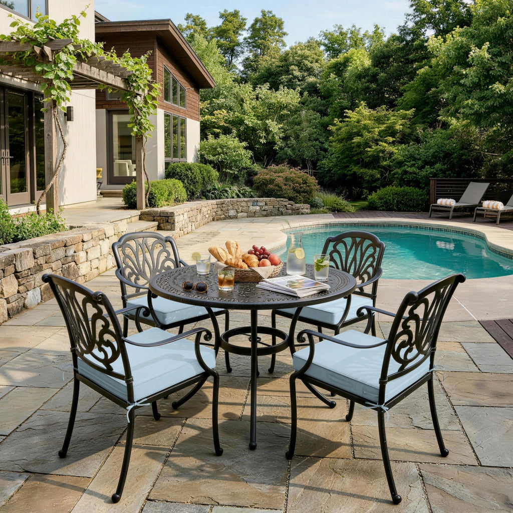 outdoor seat cushions in light blue on black metal patio dining chairs, shown around a round table beside a backyard pool