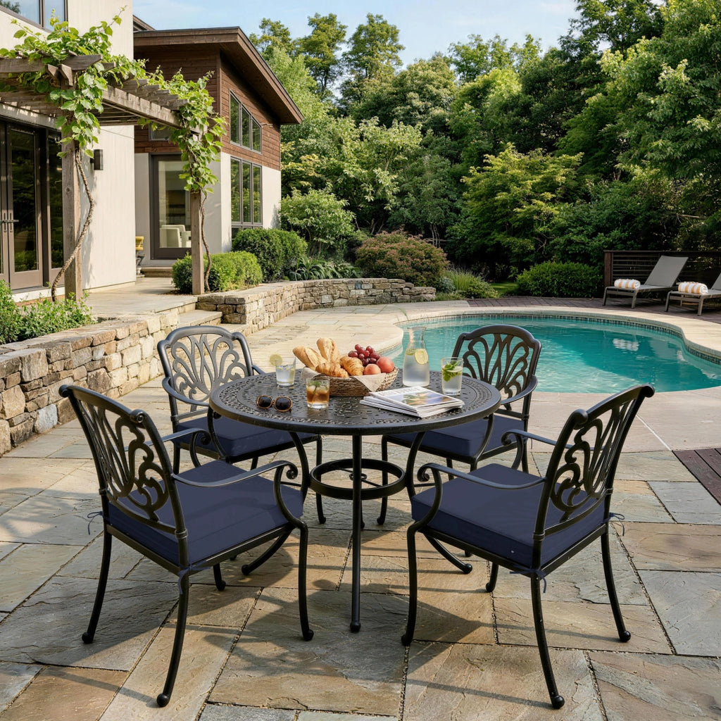 outdoor seat cushions in navy blue on black metal patio dining chairs, styled beside a backyard pool with a round outdoor table