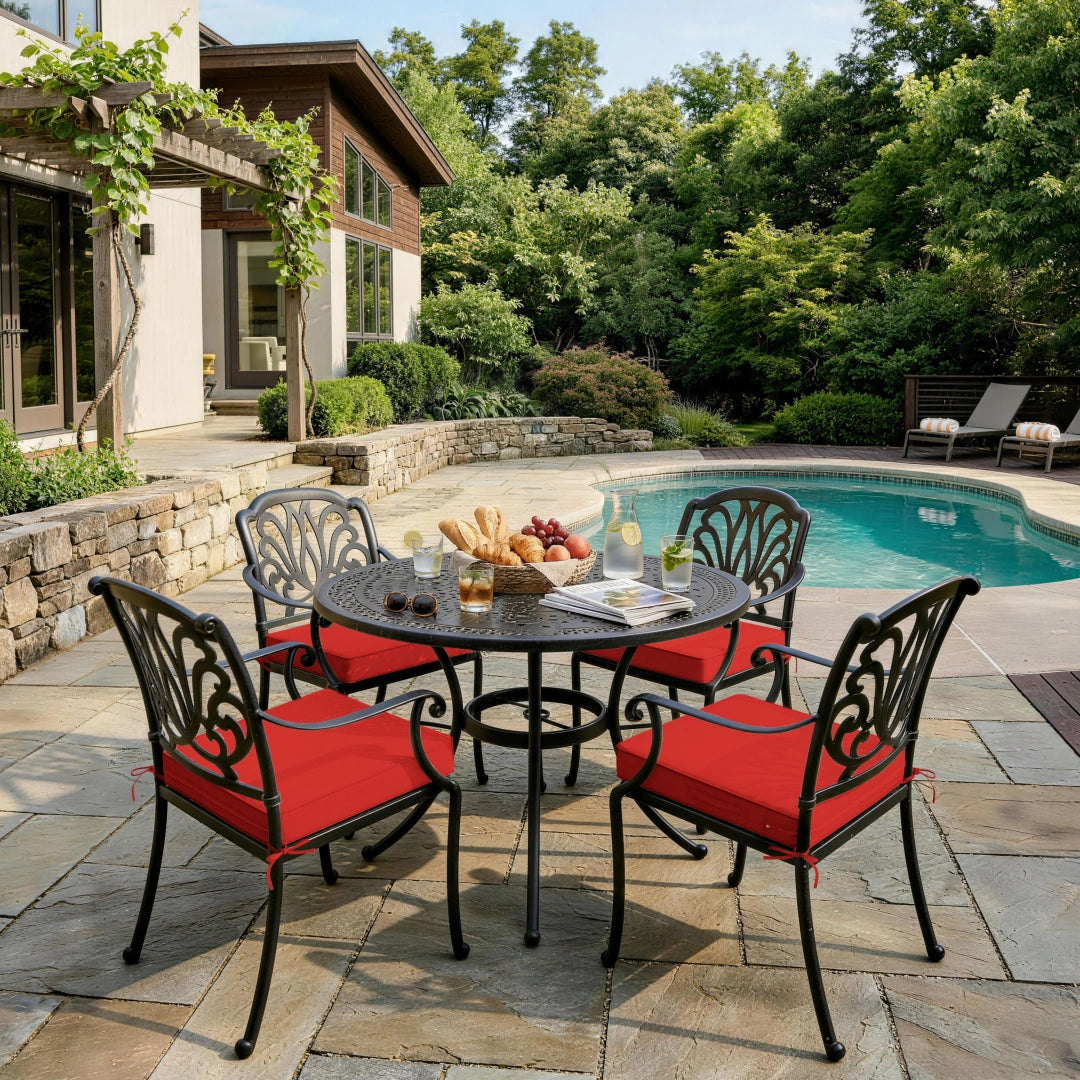 outdoor seat cushions in red on black metal patio dining chairs, styled around a round outdoor table beside a backyard pool