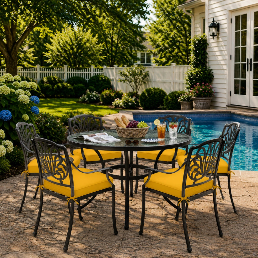 outdoor seat cushions in yellow on black metal patio chairs, styled in a sunny backyard garden with a small round outdoor table
