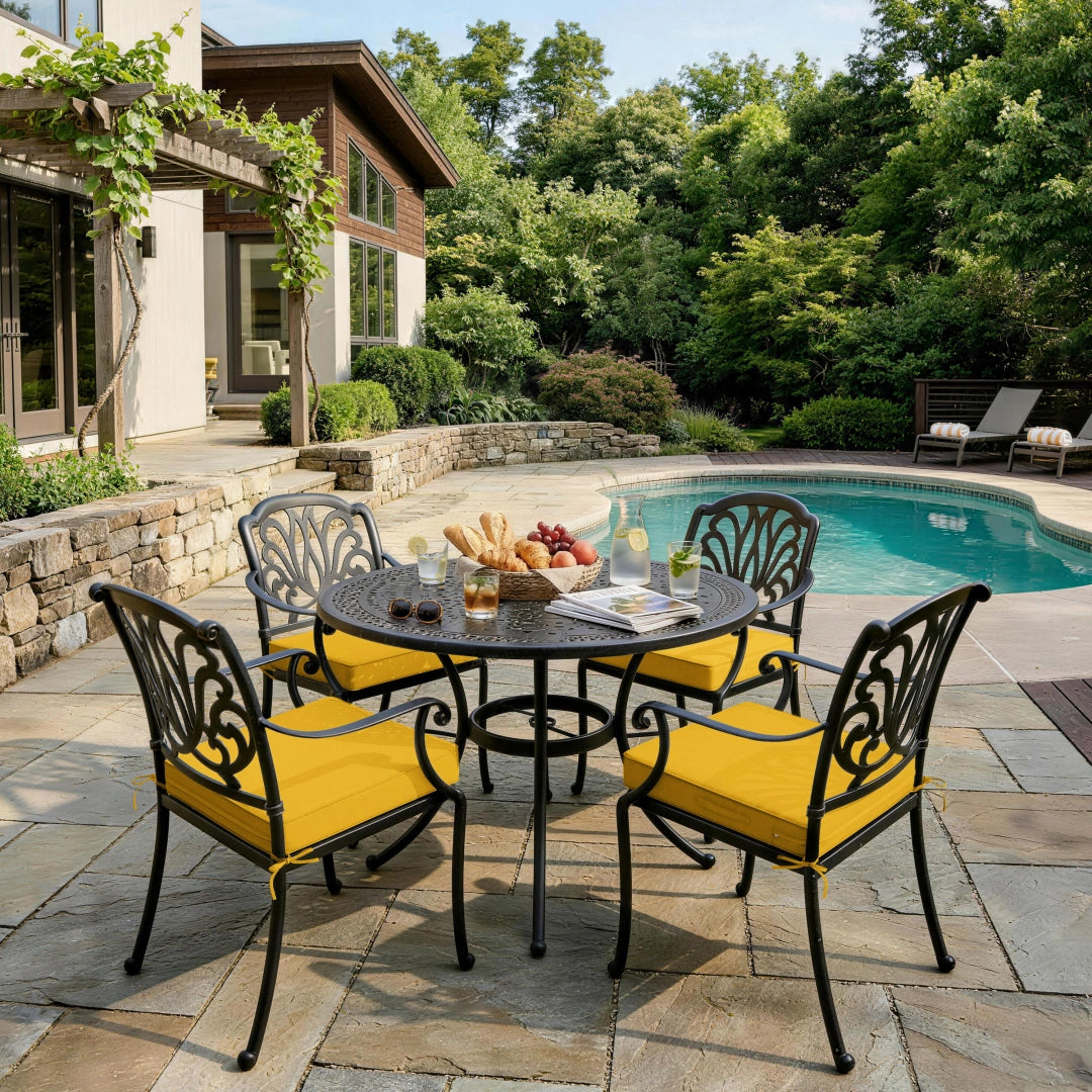 outdoor seat cushions in yellow on black metal patio dining chairs, creating a bright poolside outdoor dining setup